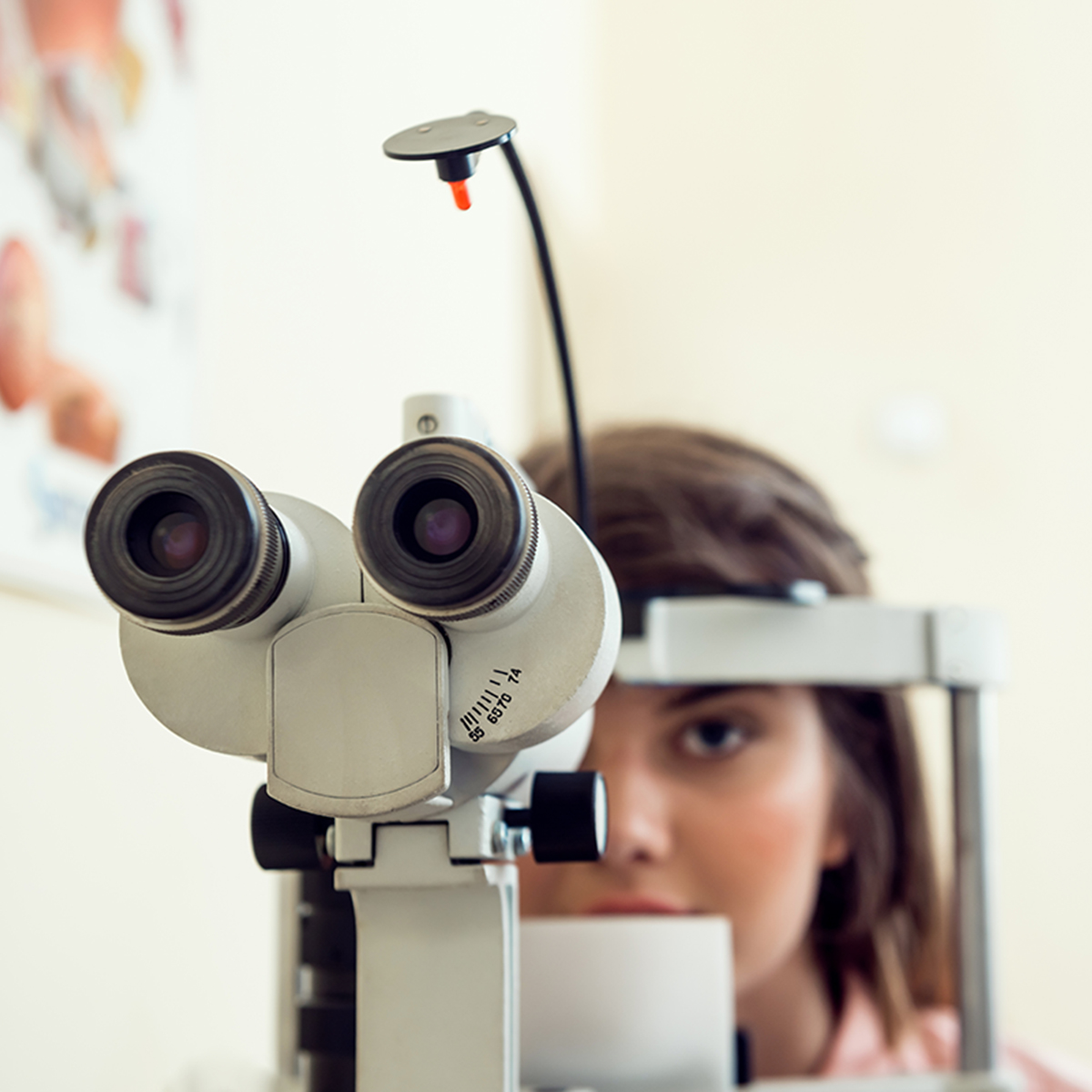 Portrait of cute caucasian female patient sitting in optometrist office, waiting for start of procedure to check her vision with microbioscope, sitting over yellow background. Ophthalmology concept Portrait of cute caucasian female patient sitting in optometrist office, waiting for start of procedure to check her vision with microbioscope, sitting over yellow background. Ophthalmology concept.