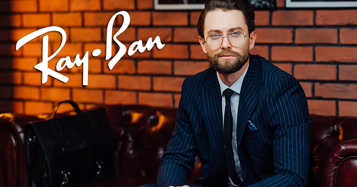 Handsome businessman wearing fashion eyeglasses and stylish suit sitting on the sofa at modern studio.